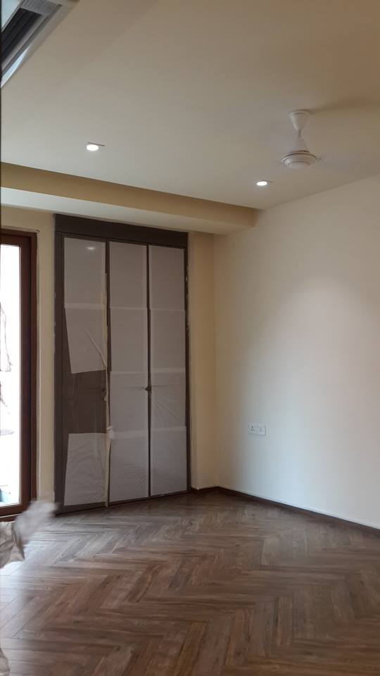 Master bedroom with herringbone wood flooring and recessed false ceiling lighting — GK I Residence