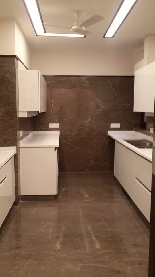Full kitchen view showing three-run layout with continuous overhead storage and dark marble backsplash — Green Park Residence