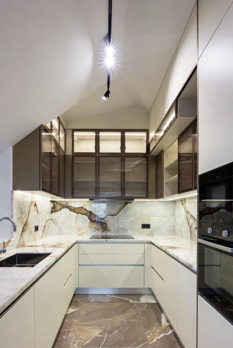 Cream handleless kitchen with full-slab Onyx marble backsplash — Re:Room