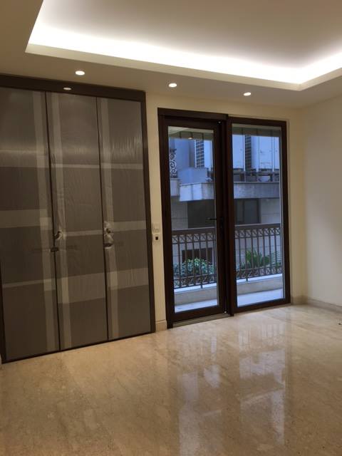 Master bedroom with upholstered headboard wall, herringbone wood floor and full-height fitted wardrobes — Maharani Bagh Residence