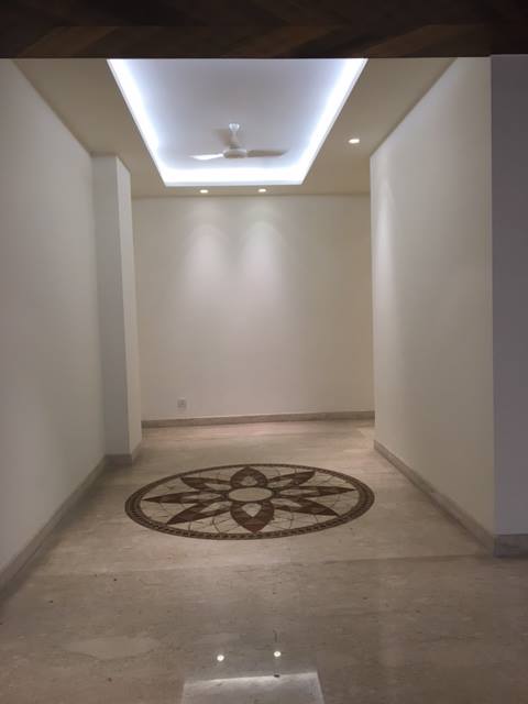 Grand foyer with white marble flooring and glass staircase — Maharani Bagh villa, New Delhi