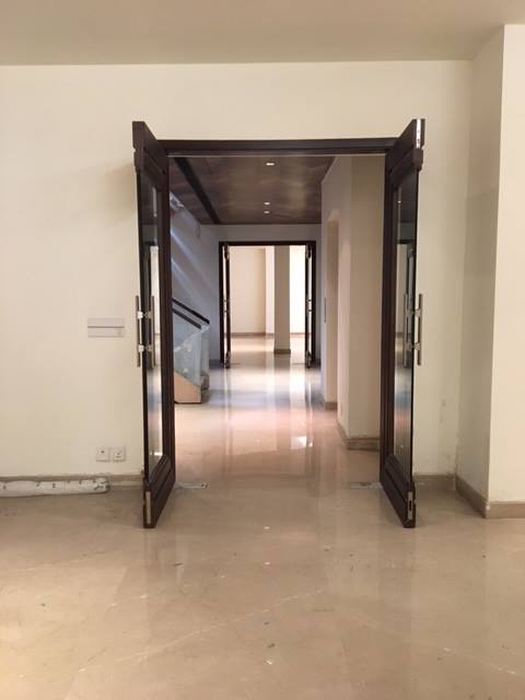 First-floor hallway with recessed niches, continuous marble floor and gallery-style lighting — Maharani Bagh Residence