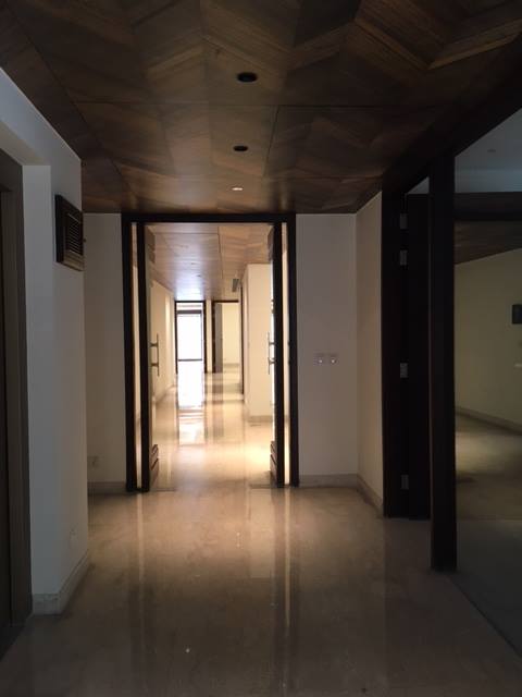 Upper floor corridor with warm recessed lighting and continuous flooring connecting bedroom suites — Maharani Bagh Residence