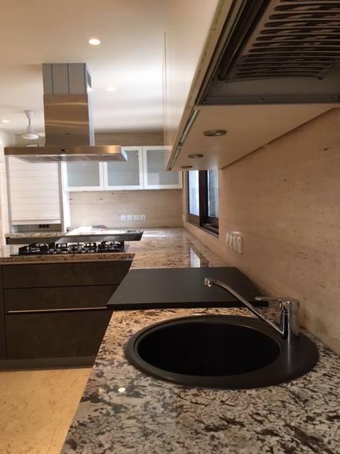 Island kitchen with single-slab stone countertop, full-height upper cabinets and integrated appliances — Maharani Bagh Residence