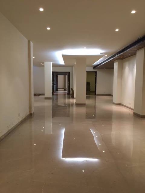 Family living room on first floor with engineered wood floor, sectional sofa and integrated media wall — Maharani Bagh Residence