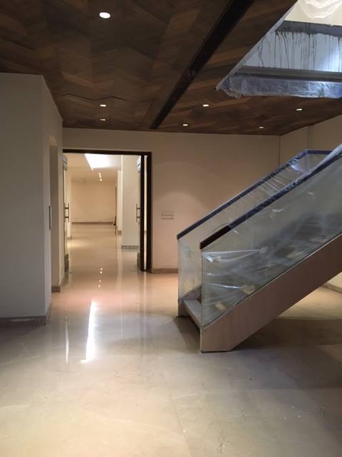 Glass staircase detail showing brushed steel handrail, step lighting and upper floor landing — Maharani Bagh Residence